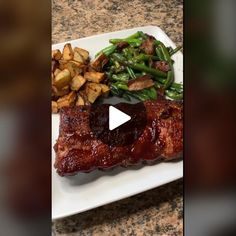 a white plate topped with meat and veggies next to a pile of potatoes