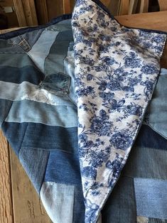 a blue and white patchwork piece of cloth on top of a wooden table next to an old pair of jeans