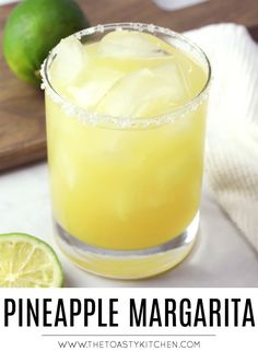 a pineapple margarita in a glass next to limes