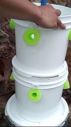 a person holding a blue and green object in their hand next to a white bucket