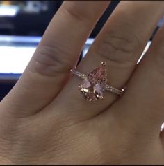 a woman's hand with a pink diamond ring on it