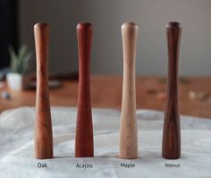 three different types of wooden baseball bats sitting on a white tablecloth with a plant in the background