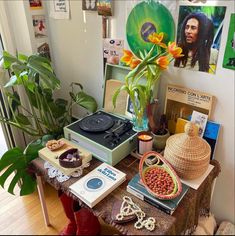 a table topped with lots of assorted items and a potted plant in the corner