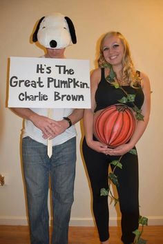 a man and woman standing next to each other holding a sign that says it's the great pumpkin charlie brown