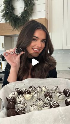 a woman holding up a box full of chocolates