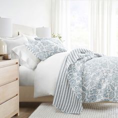 a bed with white and blue comforters in a bedroom