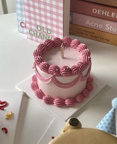 a pink and white cake sitting on top of a table next to two bookends