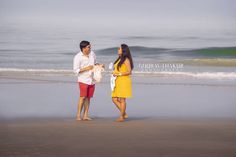 a man and woman standing on the beach next to the ocean with waves in the background