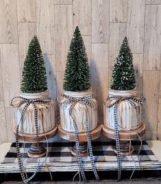 three small christmas trees are placed in mason jars