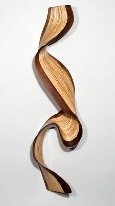 a wooden sculpture that is shaped like a curved wave on a white wall, with wood grain