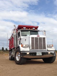 a red and white truck is parked on the dirt