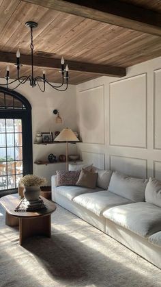 a living room filled with furniture and a chandelier hanging over the top of it