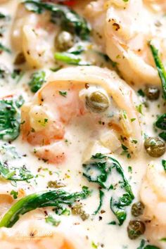 a close up view of some food with broccoli and shrimp in sauce on it