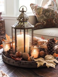 a tray with candles, pine cones and other decorations on top of a wooden table