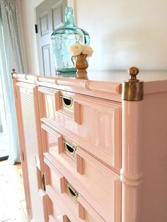 a pink dresser with gold handles and knobs