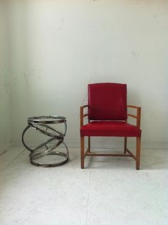 a red chair sitting next to a glass table on top of a white tile floor