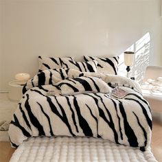 a zebra print comforter set on a bed in a room with white walls and flooring