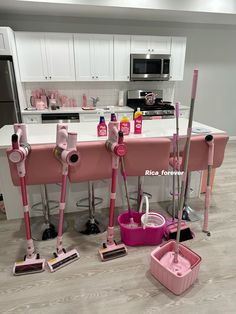 several pink mop's and buckets on the floor in front of a kitchen island