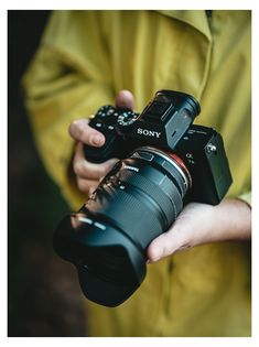 a person holding a camera in one hand and a lens in the other with both hands