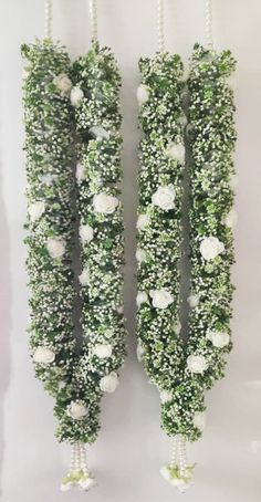 two green and white flowers are hanging from the side of each other with pearls attached to them