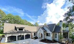 a large white house with two garages and lots of trees in front of it