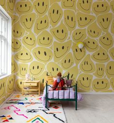 a child's room decorated in yellow and white with smiley faces on the wall