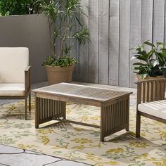 two chairs and a table on a patio with potted plants in the back ground