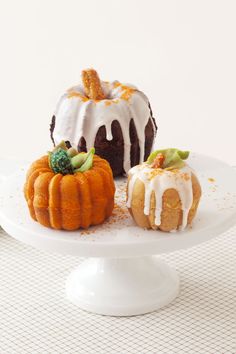 two bundt cakes sitting on top of a white cake plate next to each other