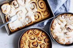 two pans filled with cinnamon rolls covered in icing next to another pan full of cinnamon rolls