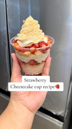 someone holding up a dessert in front of a freezer with the words strawberry cheesecake cup recipe on it