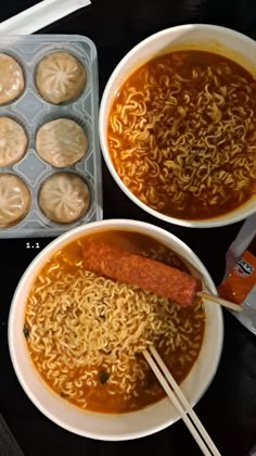 two bowls of soup with chopsticks and muffins in the back ground