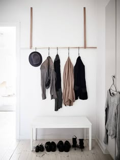 a white bench sitting next to a coat rack filled with hats and scarves on hooks