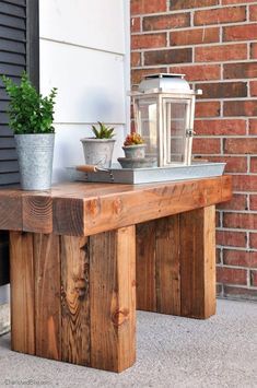 a wooden bench sitting in front of a brick wall next to a potted plant