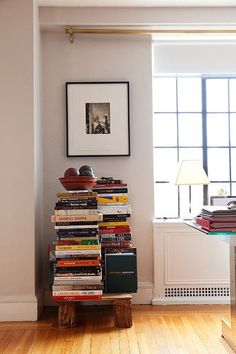 a stack of books sitting on top of a wooden table in front of a window