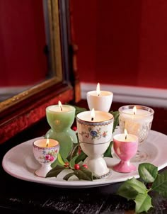 a white plate topped with lots of candles on top of a table next to a mirror