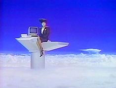 a woman in a suit sitting on top of a computer monitor above the clouds with her legs crossed