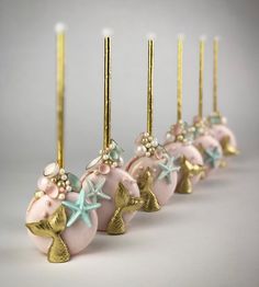 a row of pink and gold christmas ornaments with starfish decorations on them, along with candles