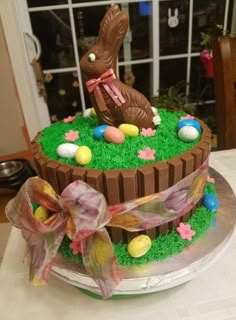 a cake decorated with grass, eggs and a bunny sitting on it's side