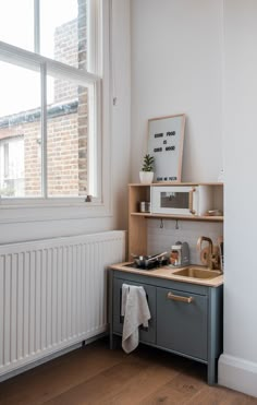 a small kitchen with a sink, stove and radiator next to a window