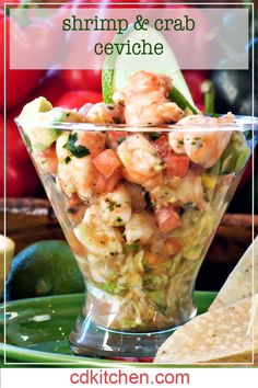 a bowl filled with shrimp salad next to tortilla chips and tomatoes in the background