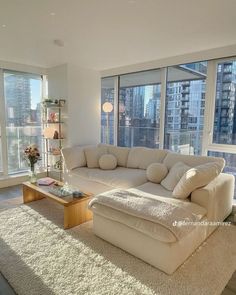 a living room filled with furniture next to large windows and a rug on the floor