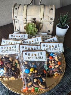 several bags of happy trails are on a table next to a trunk and potted plant