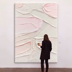 a woman standing in front of a large painting