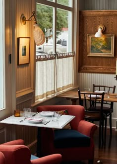 two red chairs sitting next to each other in front of a table with plates and glasses on it