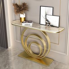 a gold and white console table with a clock on the wall behind it, next to a plant