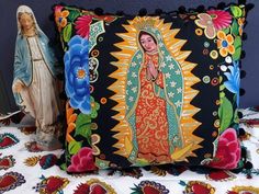 a pillow with an image of the virgin mary on it next to a statue of jesus