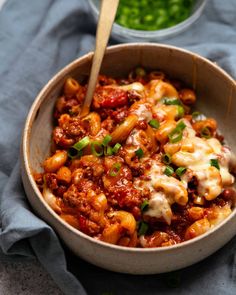 a bowl filled with pasta and sauce on top of a blue towel next to peas