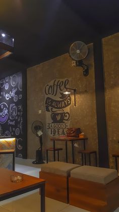 a coffee shop with tables and couches in front of a chalkboard wall that says coffee is always