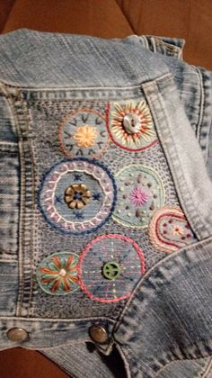 an old pair of jeans with embroidered patches and buttons on the back, sitting on a table