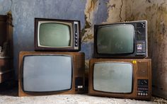 three old tvs sitting on top of each other in an abandoned room with paint peeling off the walls